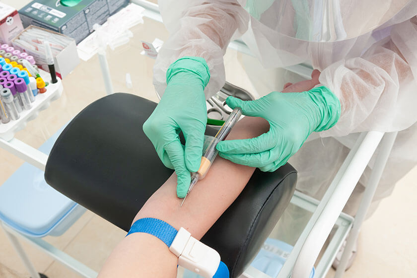 Blood sampling from a vein. A nurse in a protective suit takes blood for coronavirus antibodies, phlebotomy skills for resume