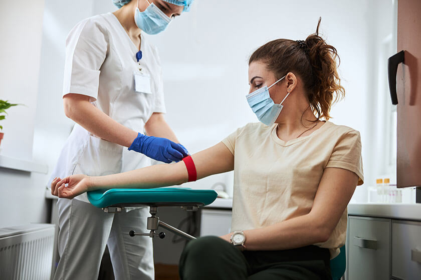 Experienced phlebotomist preparing a woman for blood draw, can a medical assistant work as a phlebotomist