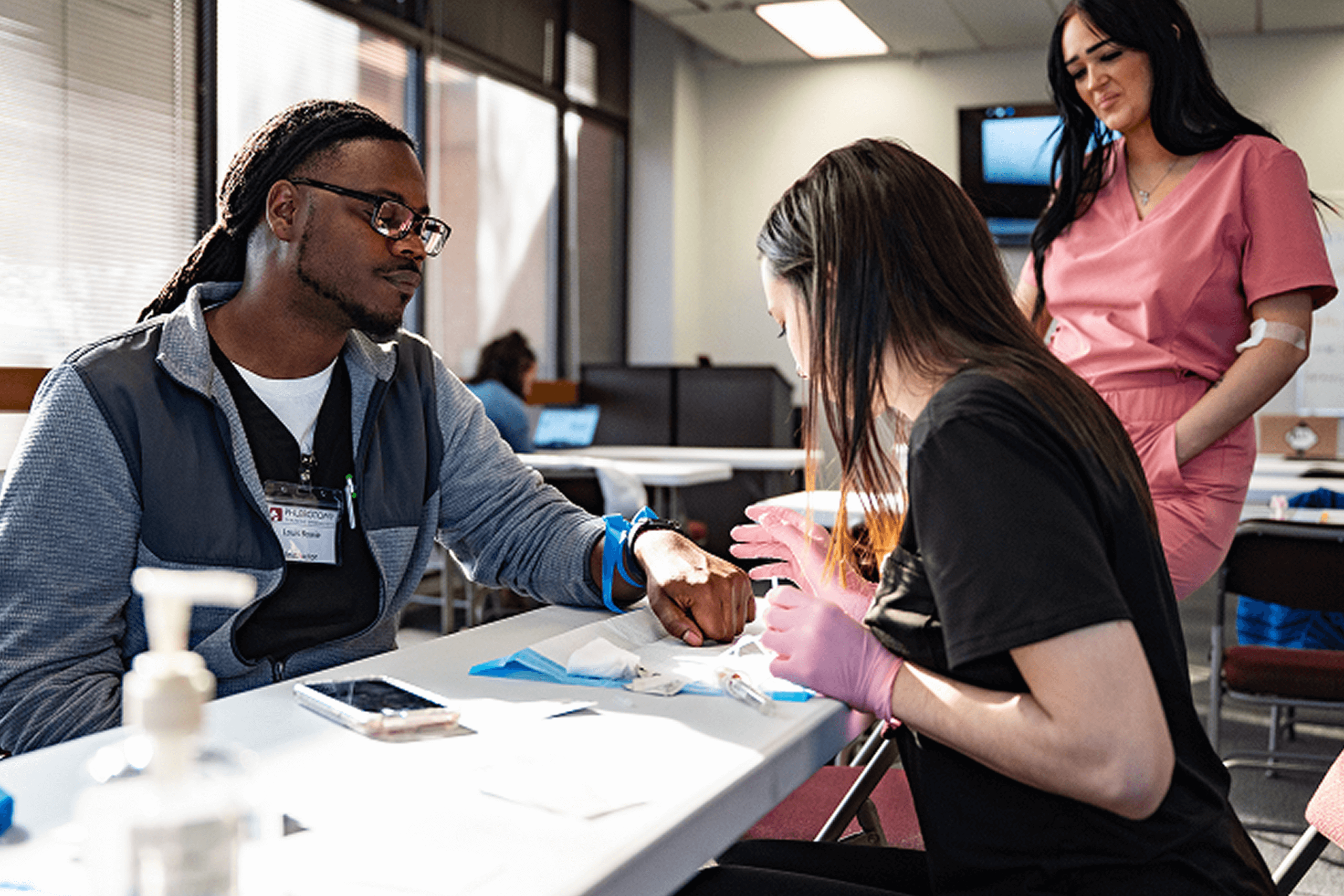 Phlebotomy Teacher teaching Phlebotomy Student taking real blood draw.